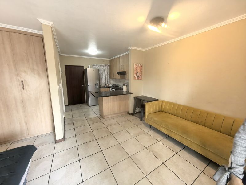 Open-plan living area featuring a compact kitchen with granite countertops, built-in cabinetry, and tiled flooring throughout.