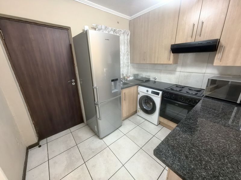 Compact kitchen featuring granite countertops, laminate cabinetry, built-in oven with hob, and tiled flooring, providing a functional workspace.