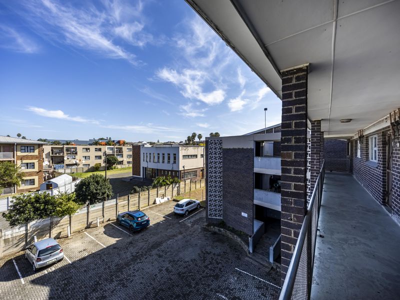 An elevated exterior walkway and balcony area overlooking the apartment complex parking lot and surrounding neighborhood.