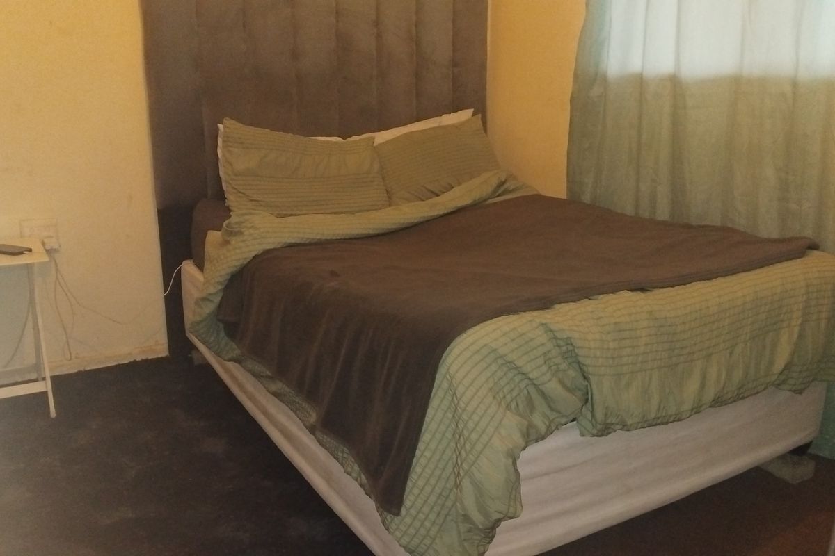 A bedroom featuring a neutral wall finish and an upholstered headboard, providing a functional sleeping space.