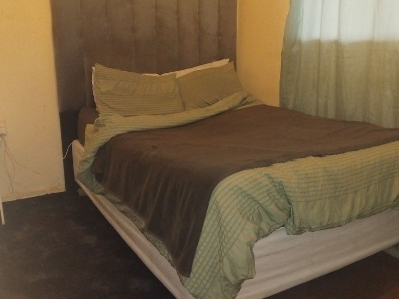 A bedroom featuring a neutral wall finish and an upholstered headboard, providing a functional sleeping space.