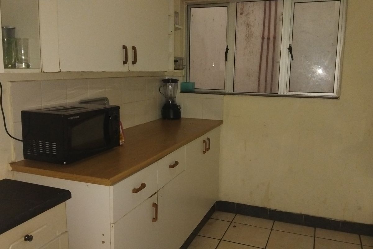 A functional kitchen featuring laminate countertops, built-in cabinetry, and tiled flooring, requiring cosmetic updates to improve its overall condition and aesthetic appeal.