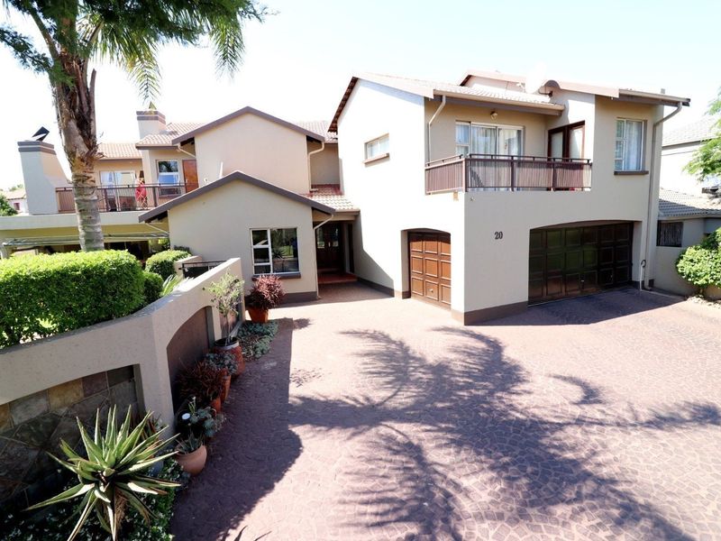 Front elevation of a multi-story residential house featuring a paved driveway, double garage, and an upper-level balcony.