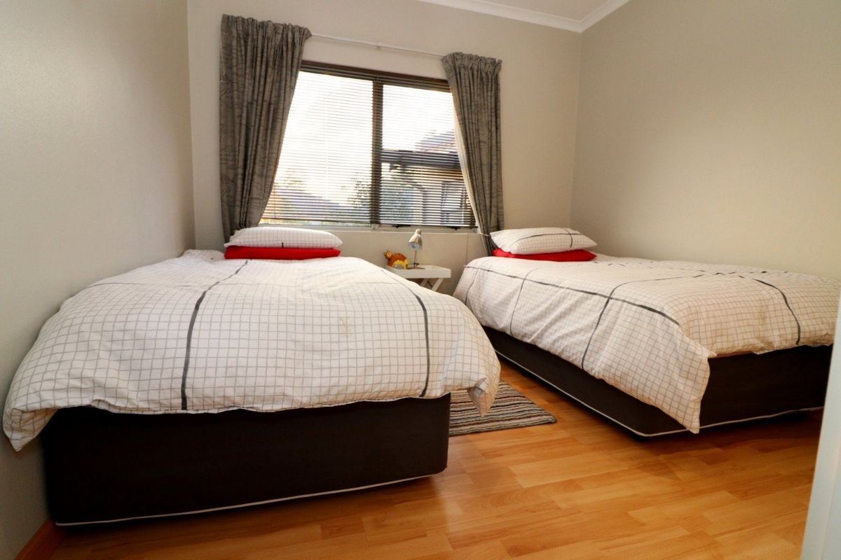 A functional bedroom featuring laminate flooring and a window with fitted blinds, providing a neutral space ready for personalization.