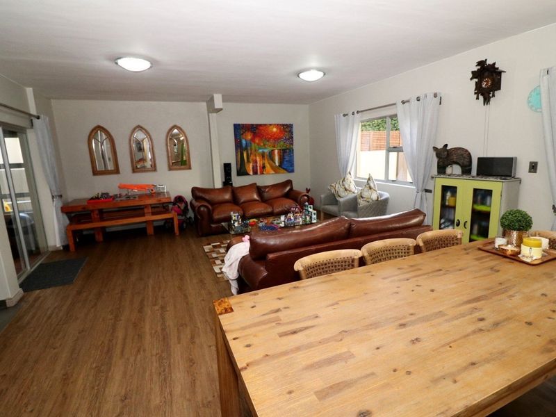 Spacious open-plan living and dining area featuring durable laminate flooring and sliding glass doors providing access to the exterior.