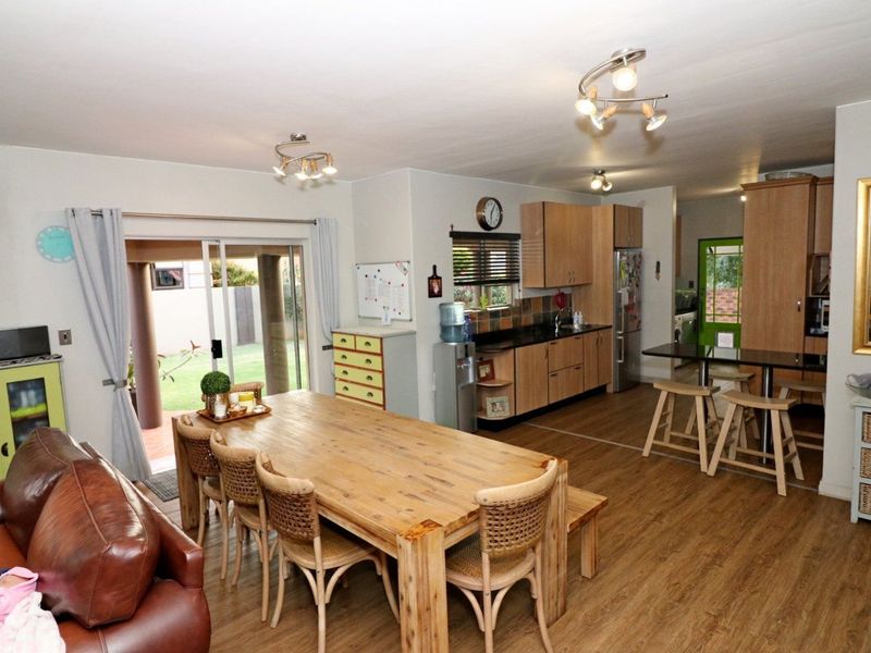 Open-plan living and dining area featuring laminate flooring, a functional kitchen with granite countertops, and sliding door access to the outdoor patio.