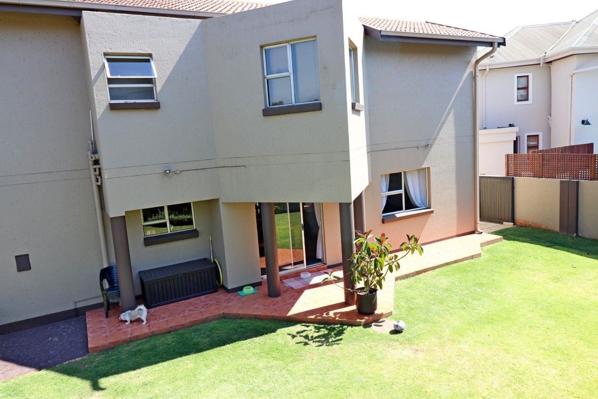 Rear view of the property featuring a tiled patio, sliding glass doors, and a private garden area with perimeter walling.