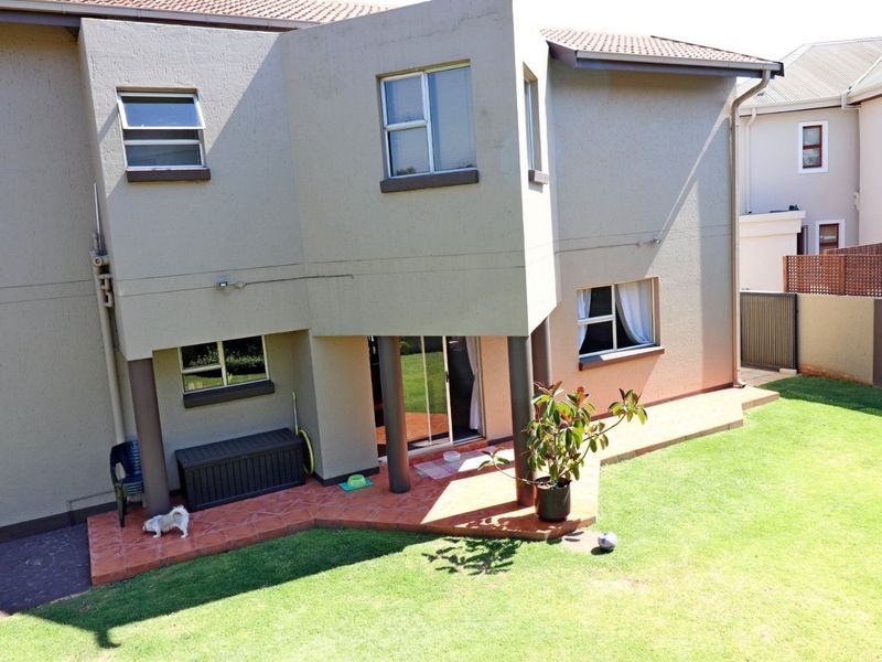 Rear view of the property featuring a tiled patio, sliding glass doors, and a private garden area with perimeter walling.