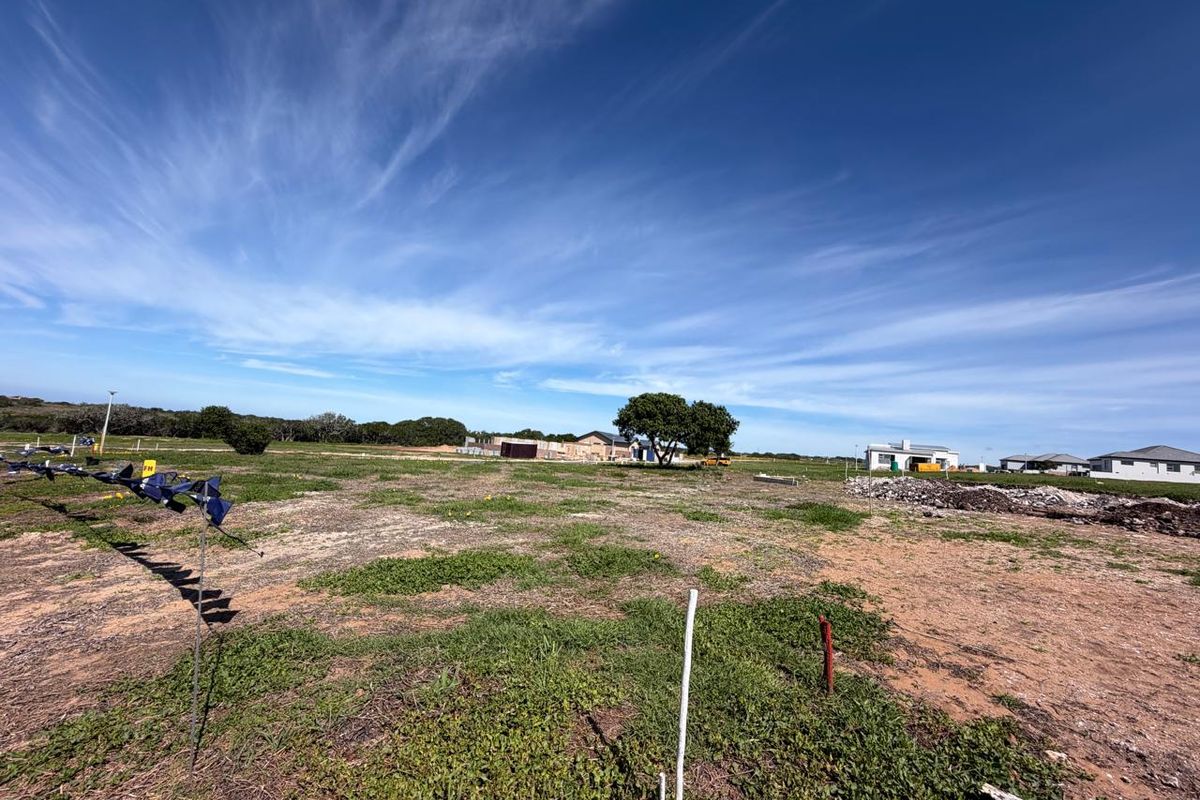 A wide-angle view of a vacant residential plot featuring natural vegetation and survey markers, ready for development in a quiet neighborhood.
