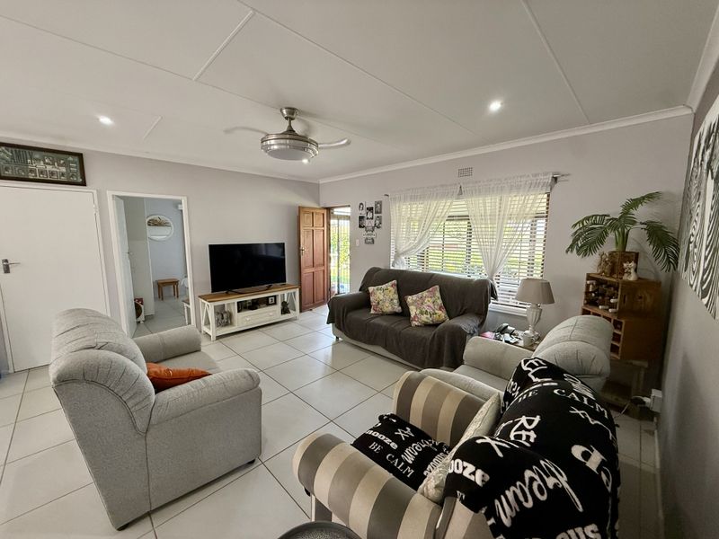 A well-lit living room featuring neutral tiled flooring, a ceiling fan, and recessed lighting, providing a comfortable and functional space for relaxation.