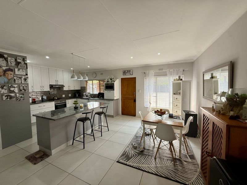 Spacious open-plan kitchen and dining area featuring a central island, modern cabinetry, tiled flooring, and ample natural light.