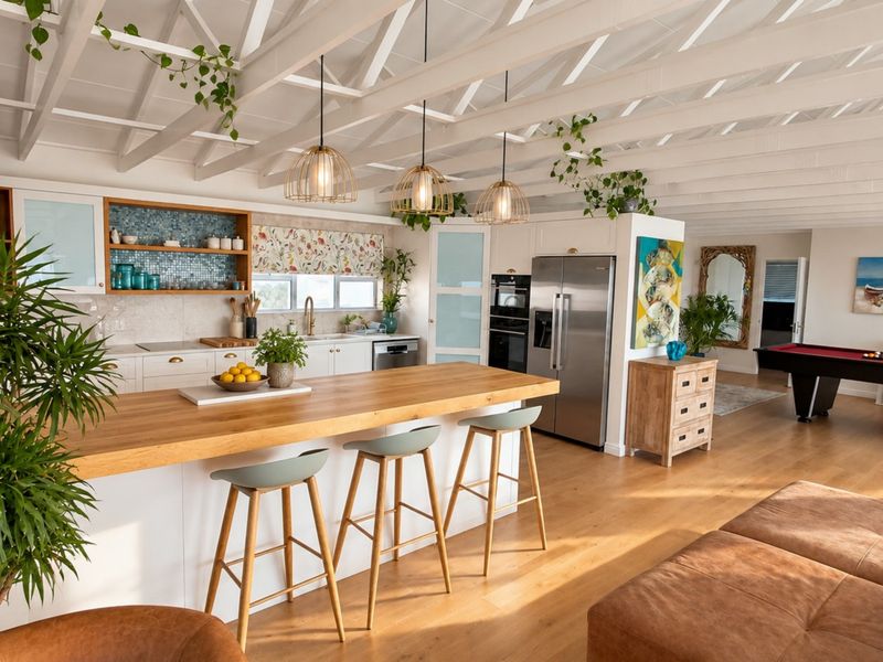 Spacious open-plan kitchen and living area featuring exposed white timber trusses, a large kitchen island with timber countertop, and modern built-in appliances.