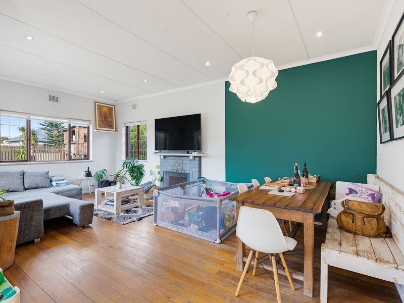 Open plan living and dining area featuring timber flooring, a fireplace, and a feature wall, providing a versatile space for family living.