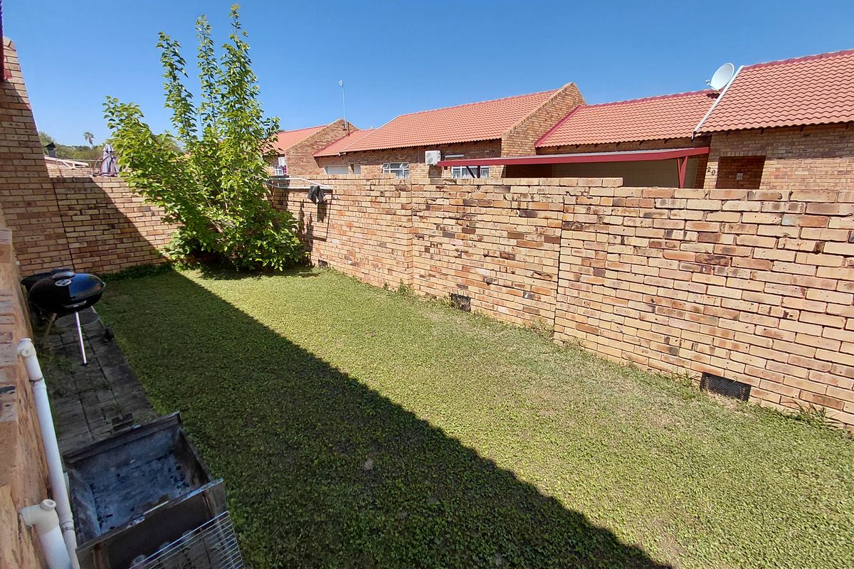 A private rear garden area featuring a lawn and brick boundary walls, typical of a townhouse property.