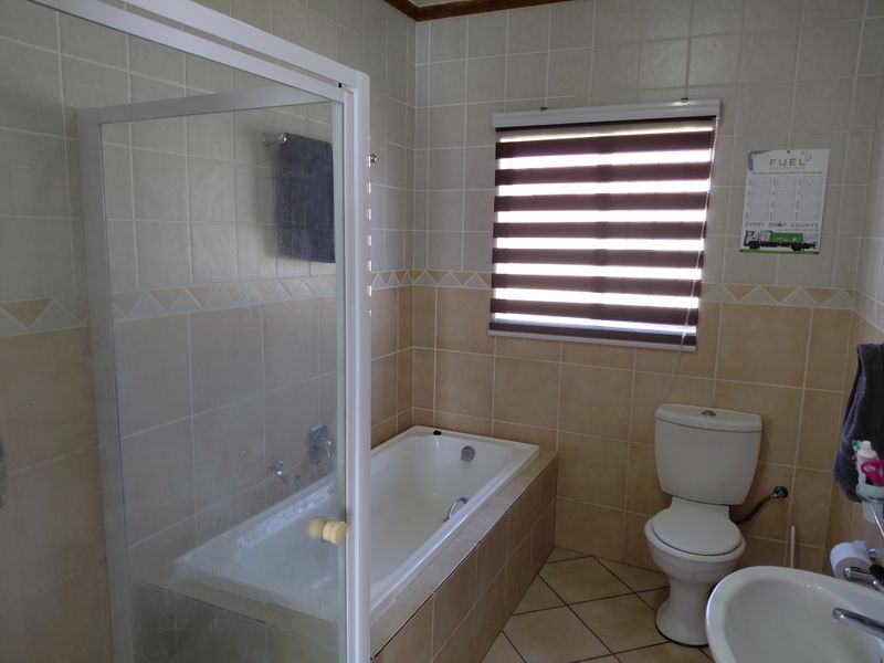 A functional bathroom featuring a built-in bathtub, separate shower enclosure, pedestal basin, and toilet with neutral ceramic wall and floor tiling.
