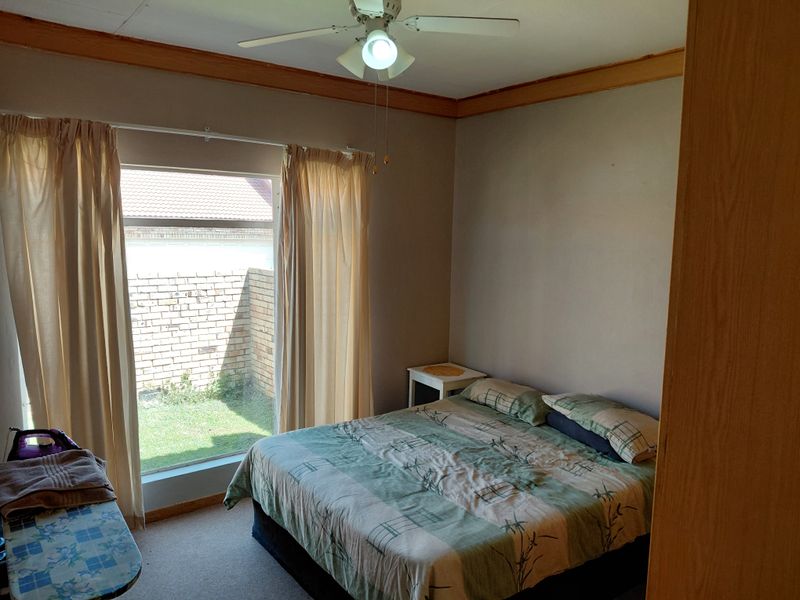 A bedroom featuring carpeted flooring, a ceiling fan, and a built-in cupboard, with direct access to a small outdoor garden area.