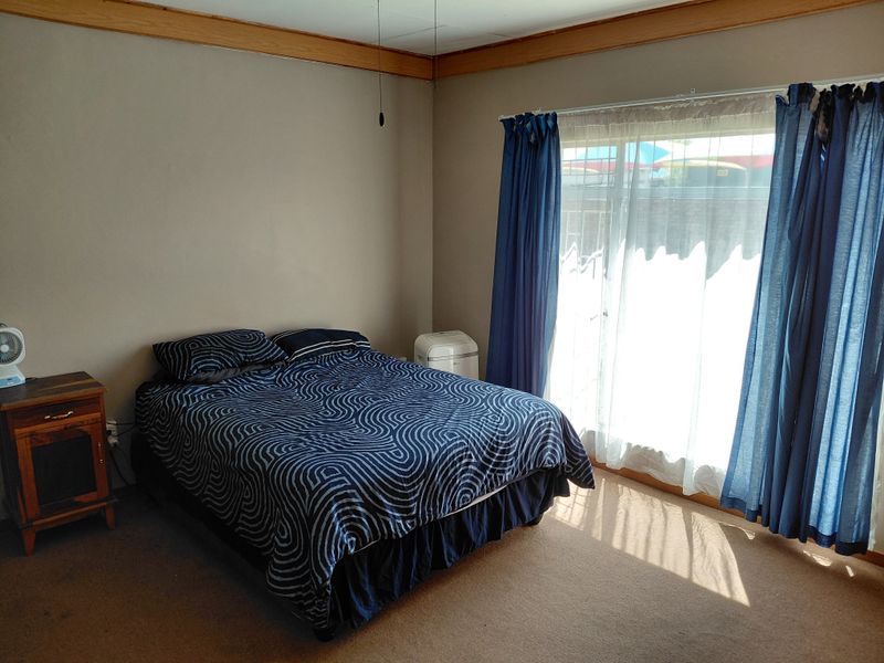 A bedroom featuring carpet flooring, a ceiling fan, and a sliding glass door providing natural light.