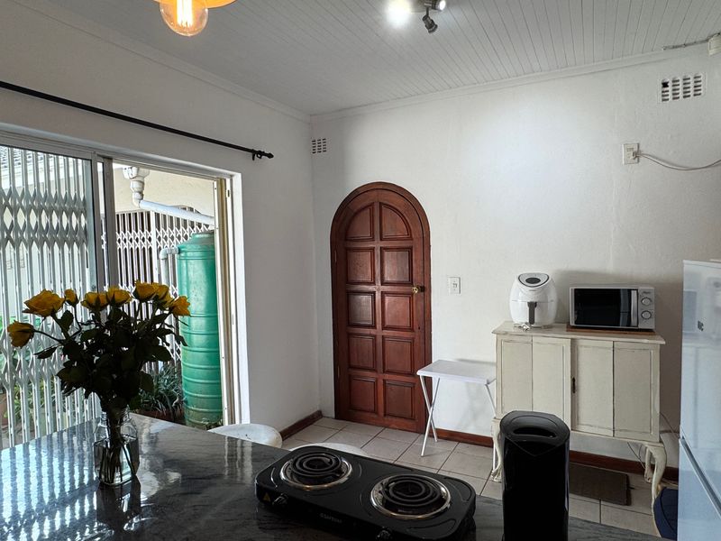 A kitchen area featuring an arch-top wooden door, tiled flooring, and a sliding glass door providing access to the exterior.