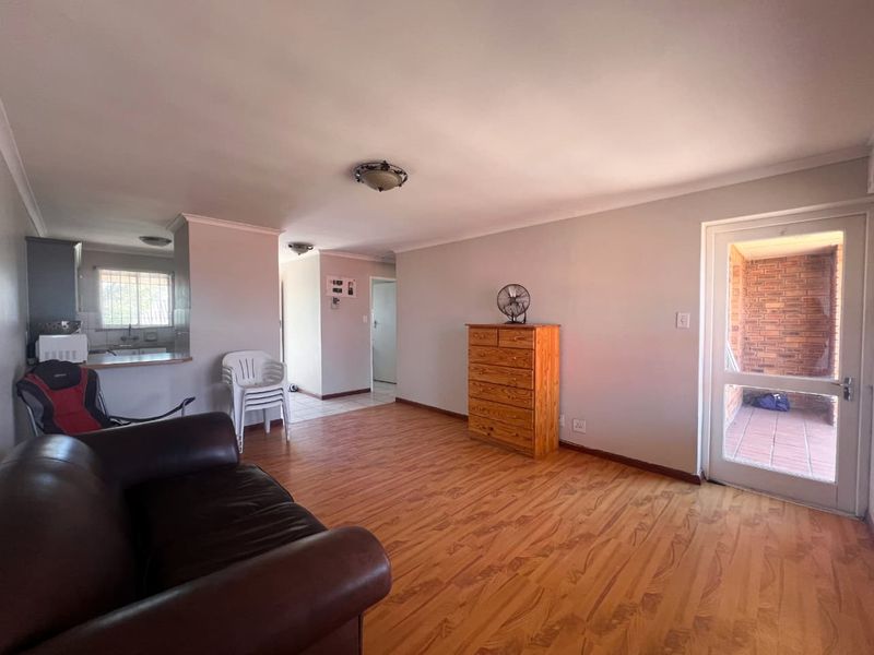 Open plan living area featuring laminate flooring, coved cornicing, and direct access to an exterior patio through a glass panelled door.
