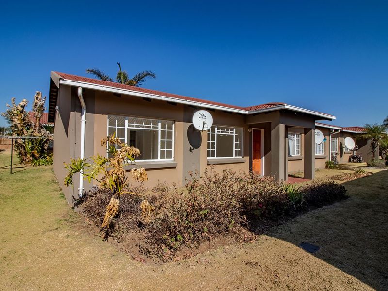Front exterior view of a townhouse featuring a tiled roof, satellite dish, and established garden area.
