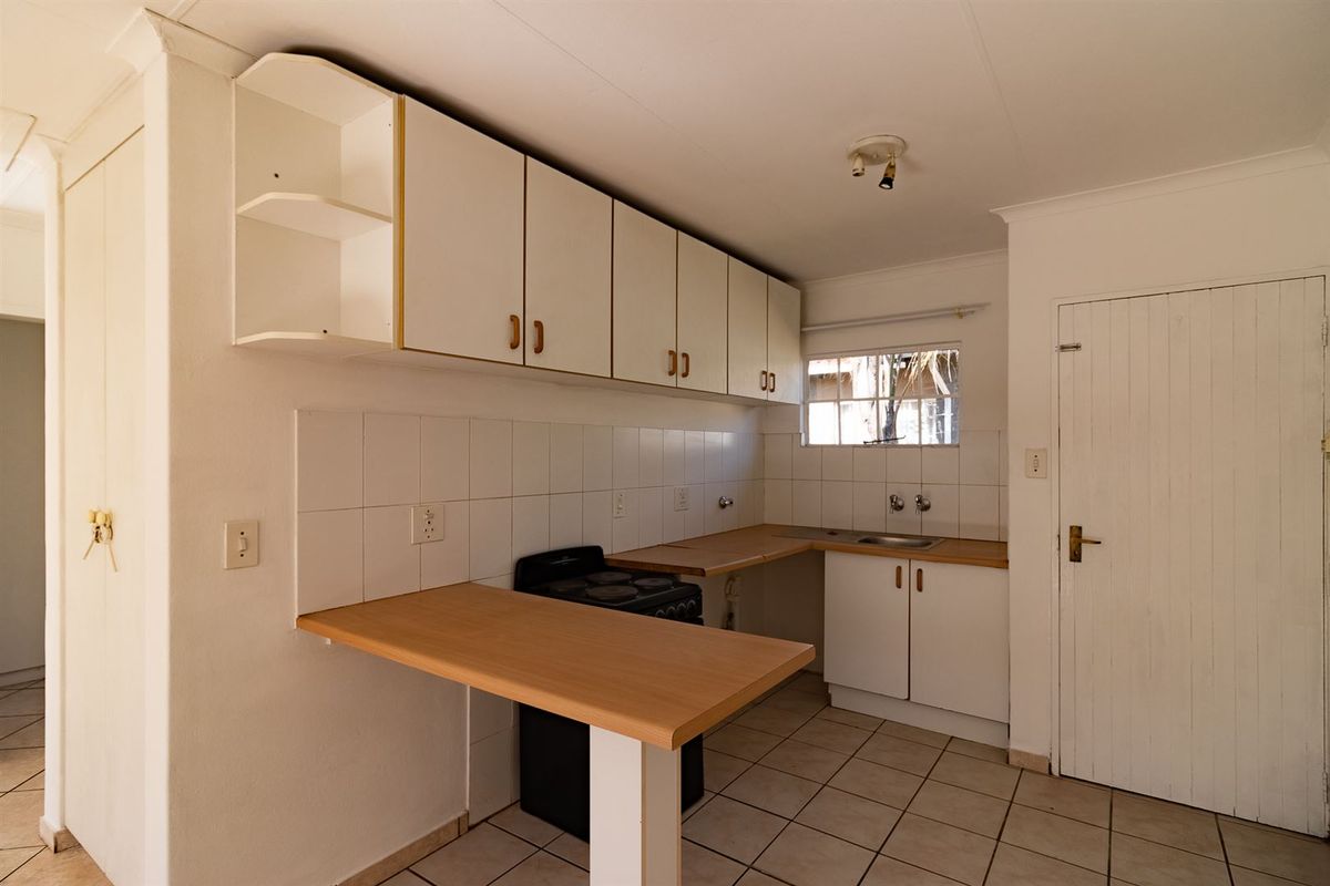 A functional kitchen featuring white cabinetry, laminate countertops, tiled backsplash, and a freestanding stove, offering a clean and practical layout.