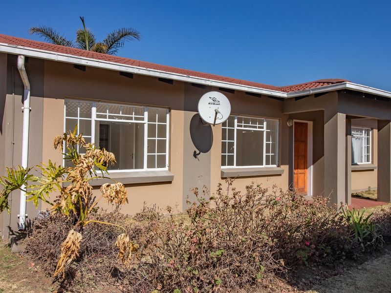 Front elevation of a townhouse featuring a tiled roof, satellite dish, and a covered entrance with a wooden door.