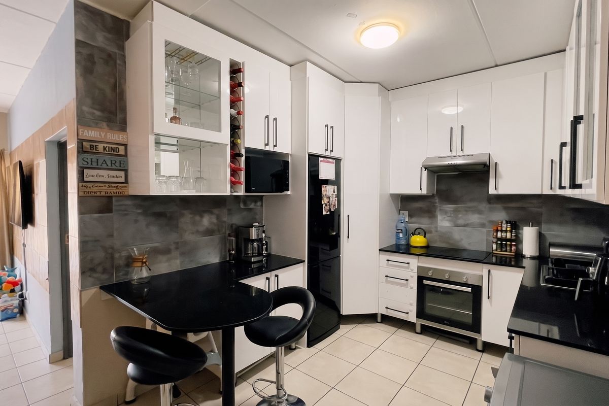 Modern kitchen featuring white cabinetry, black granite countertops, built-in oven and hob, tiled backsplash, and a convenient breakfast nook area.