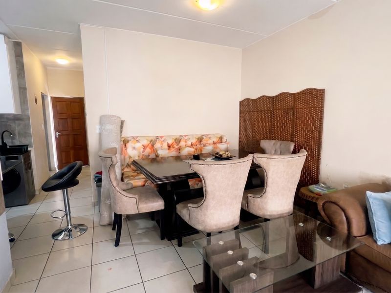 Open plan living and dining area featuring tiled flooring and a compact kitchen corner with built-in cabinetry and sink.