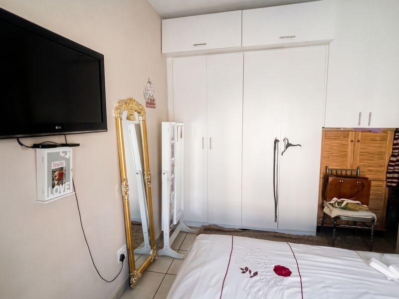 Bedroom featuring white built-in wardrobes with overhead storage cupboards and tiled flooring.