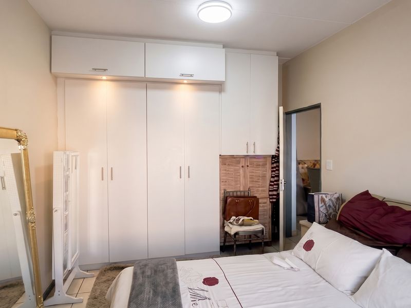 Bedroom featuring white built-in cupboards with integrated lighting and tiled flooring.