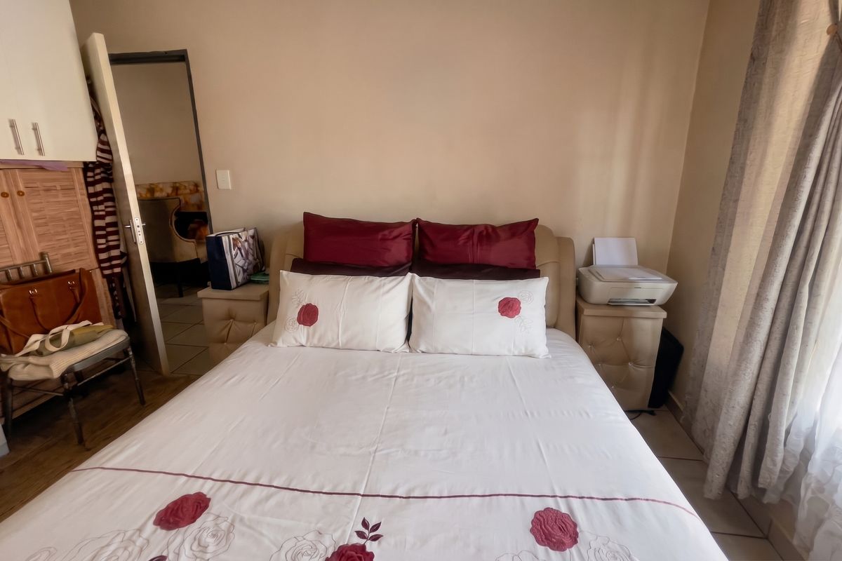 A bedroom featuring built-in wardrobe storage and tiled flooring, providing a functional sleeping space with natural light access.