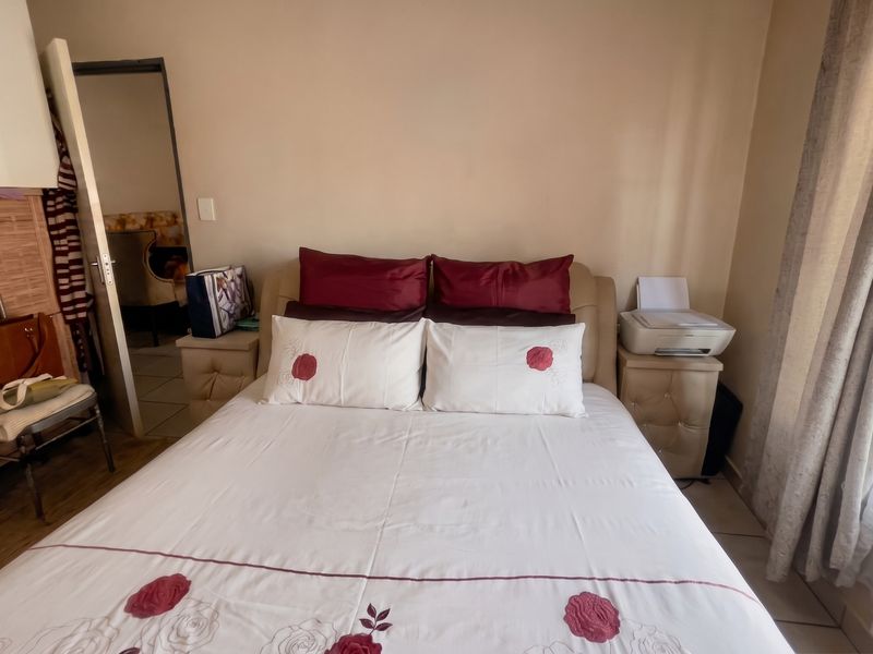 A bedroom featuring built-in wardrobe storage and tiled flooring, providing a functional sleeping space with natural light access.