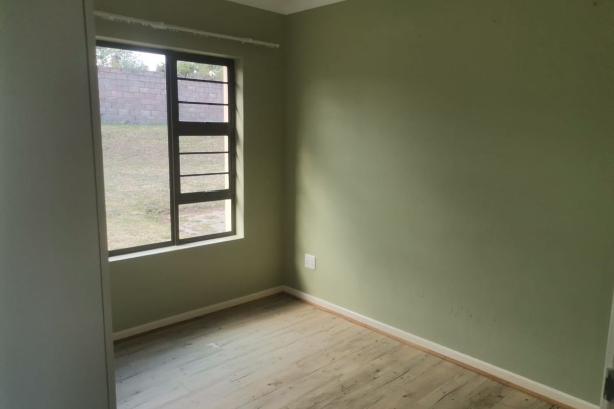 An empty bedroom featuring laminate flooring, olive green walls, and a built-in cupboard, offering a blank canvas for personalization.