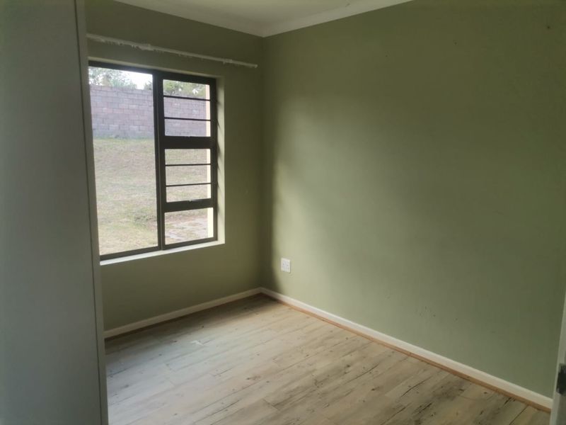 An empty bedroom featuring laminate flooring, olive green walls, and a built-in cupboard, offering a blank canvas for personalization.