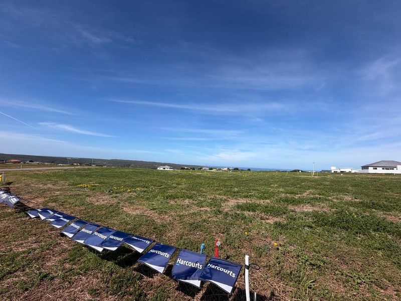 A wide-angle view of a vacant residential plot of land with surrounding neighborhood development visible in the distance.