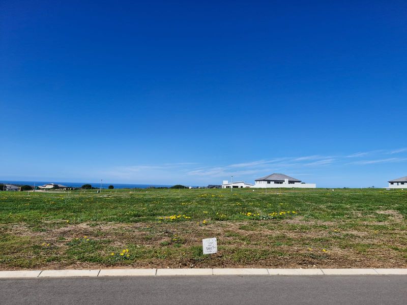 A clear, level vacant residential plot with road frontage, offering expansive views and situated in a developed coastal estate.