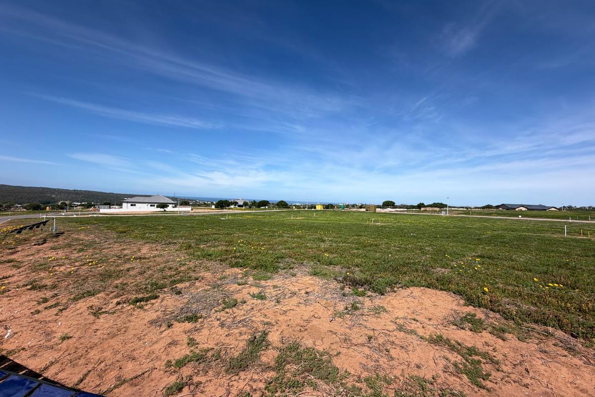 A wide-angle view of a vacant residential plot featuring natural ground cover and clear boundary markers in a developing neighborhood.