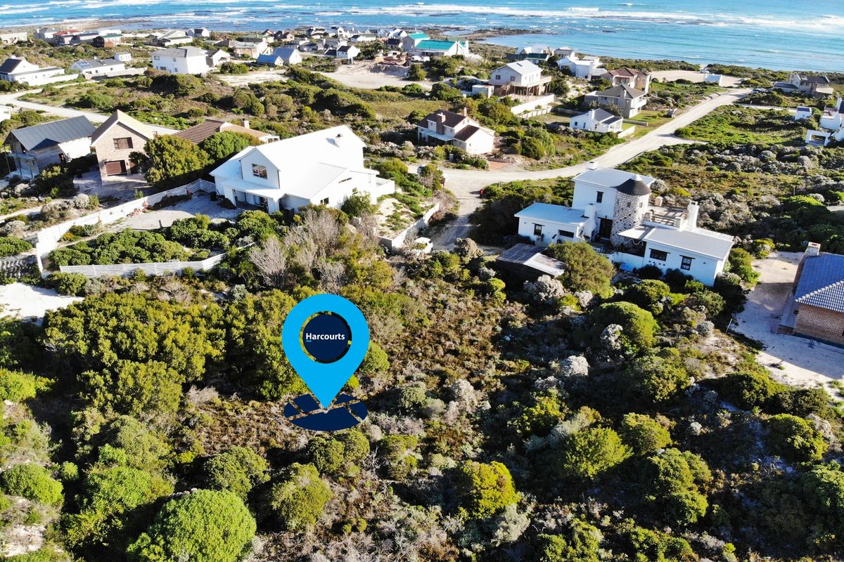 Aerial view of a vacant residential plot situated in a coastal neighborhood, surrounded by established homes and natural vegetation.