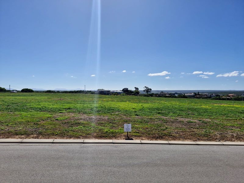 A view of a vacant residential plot from the street, featuring level ground and clear access to the road.