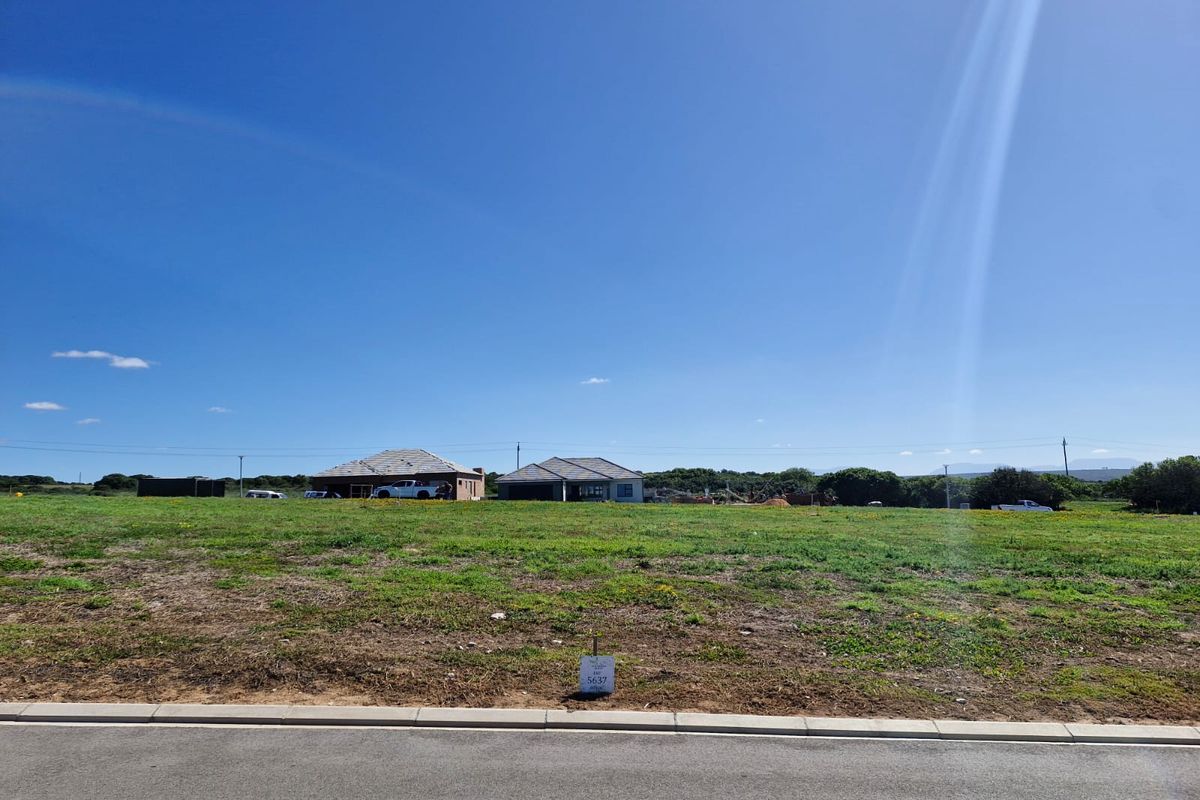 A view of a vacant residential plot from the street, featuring level ground and surrounding neighbourhood development.