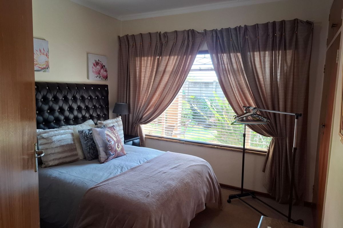 A cozy bedroom featuring a window with security bars and a built-in cupboard, providing functional storage and natural light.