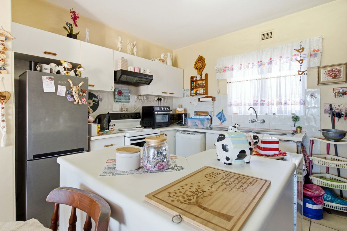 A functional kitchen featuring white cabinetry, laminate countertops, a double basin sink, and a tiled backsplash, offering a practical layout for daily meal preparation.