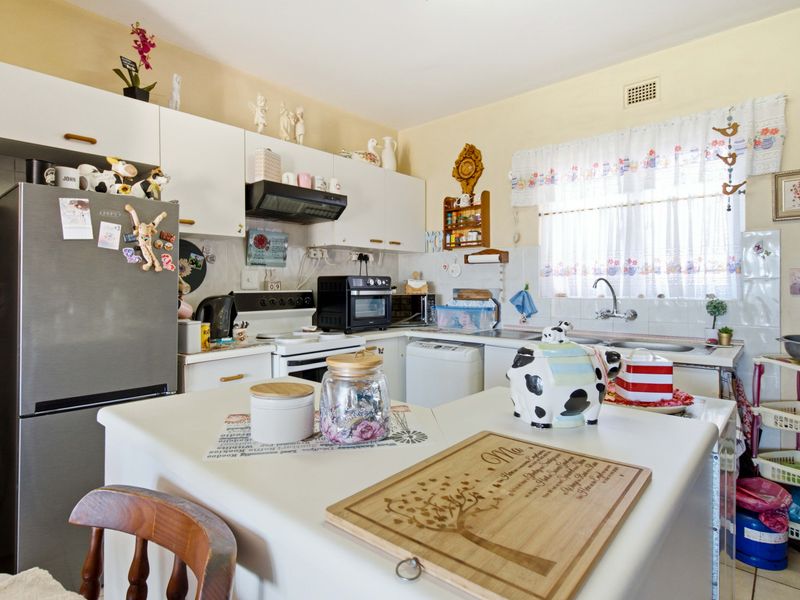 A functional kitchen featuring white cabinetry, laminate countertops, a double basin sink, and a tiled backsplash, offering a practical layout for daily meal preparation.