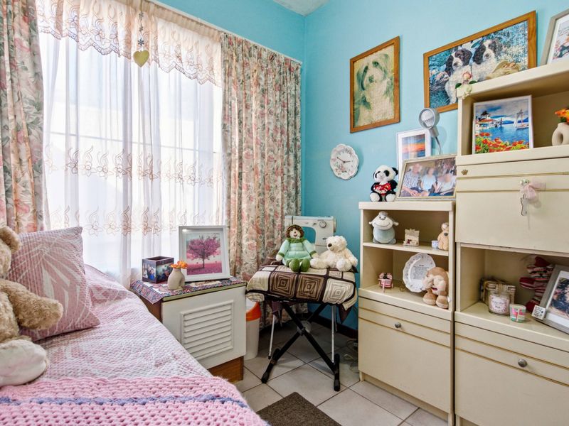 A bedroom featuring tiled flooring and a large window with curtain rails, providing natural light to the space.