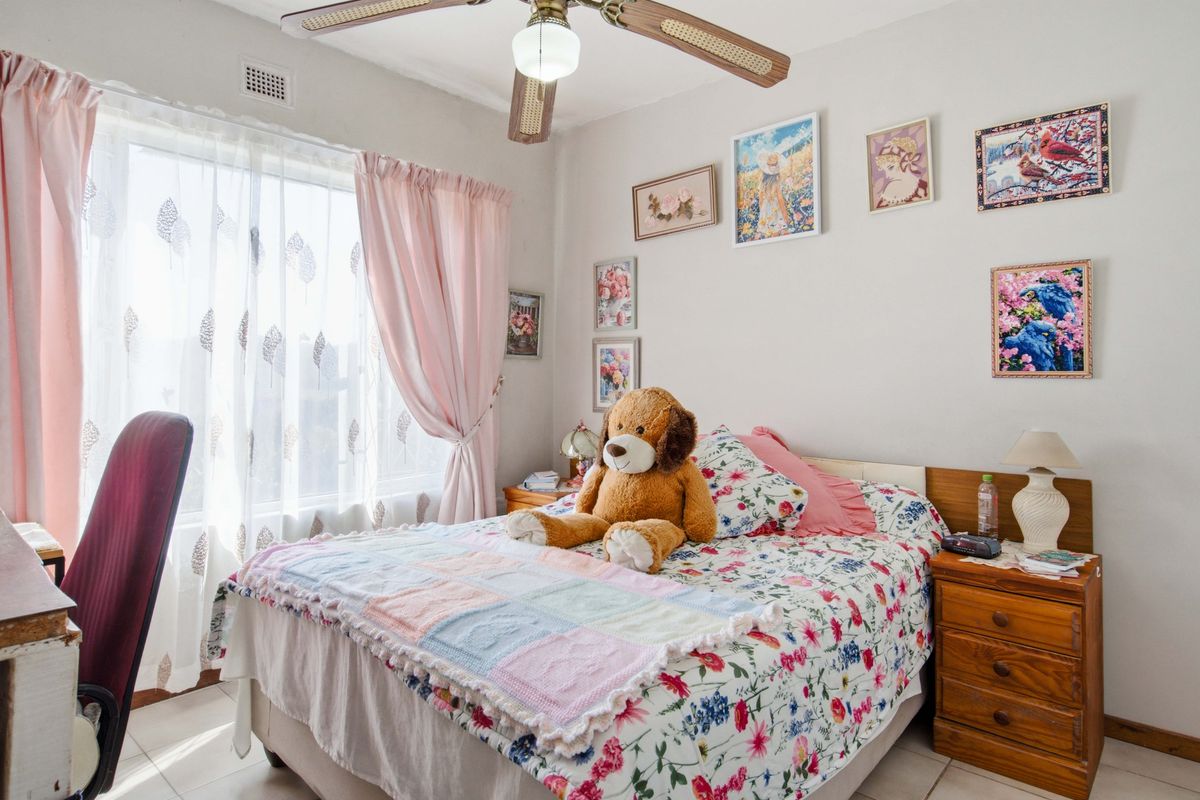 A well-lit bedroom featuring tiled flooring, a ceiling fan, and a large window allowing for natural light.