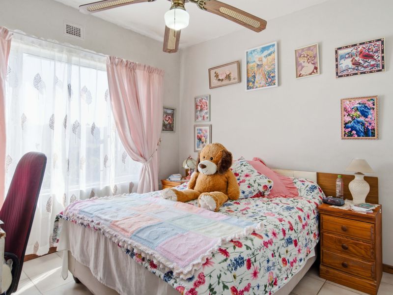 A well-lit bedroom featuring tiled flooring, a ceiling fan, and a large window allowing for natural light.