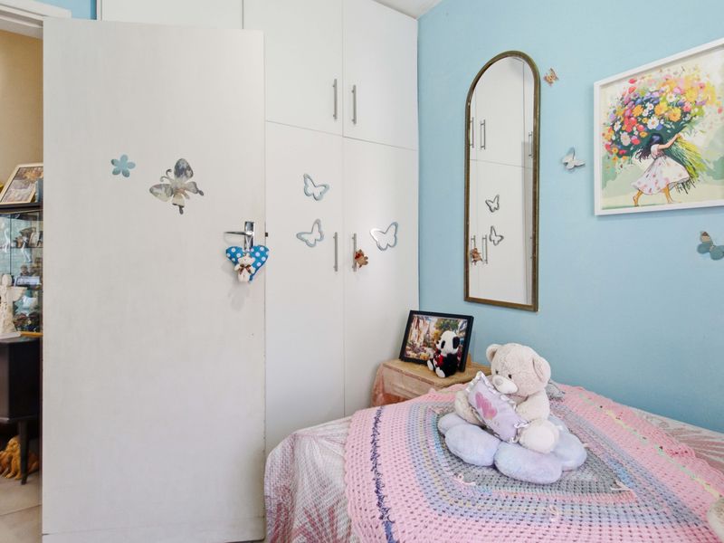 A bedroom featuring built-in cupboards and tiled flooring, providing functional storage space within the room.