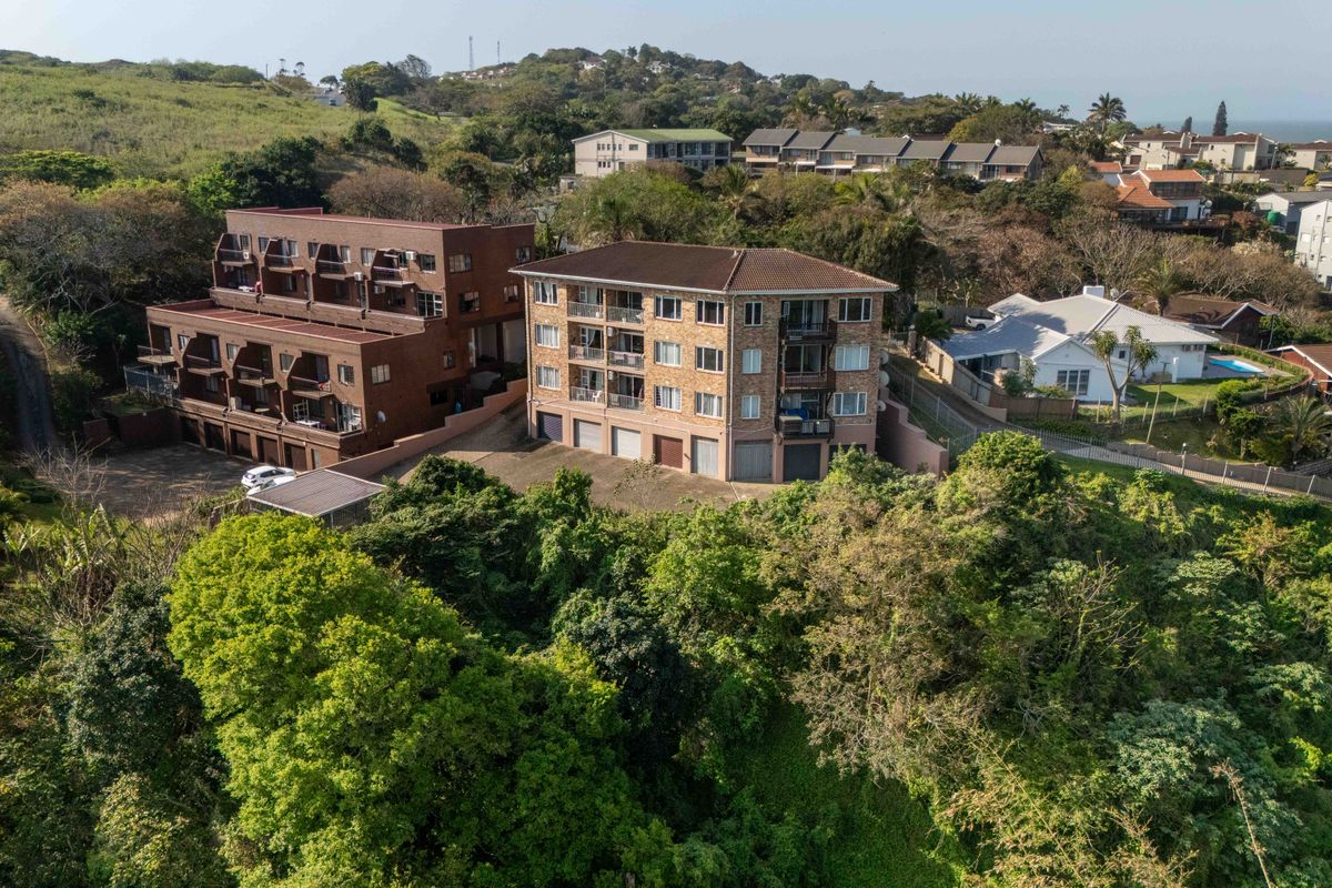 Aerial view of a multi-story residential townhouse complex featuring brick facades, tiled roofing, and integrated garage access within a landscaped estate setting.