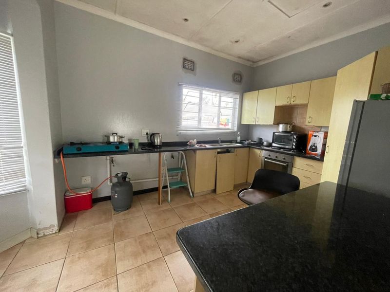 A functional kitchen featuring granite countertops, built-in cabinetry, and tiled flooring, requiring cosmetic updates to improve its overall aesthetic and condition.