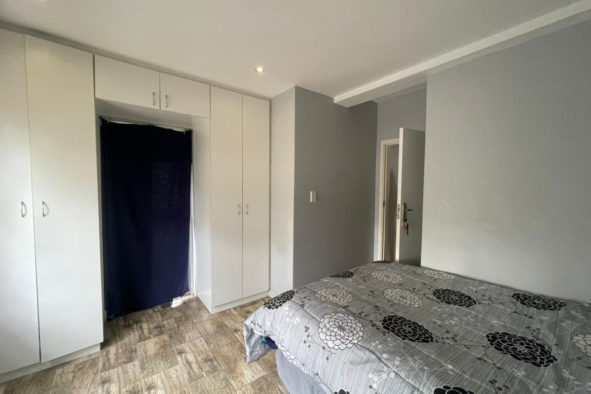 A bedroom featuring built-in cupboards, recessed downlighting, and wood-look tiled flooring.